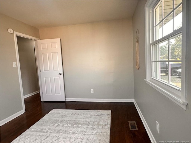 unfurnished room featuring dark wood finished floors, baseboards, and visible vents