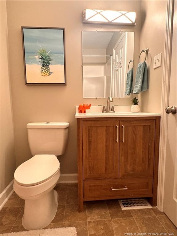 bathroom with tile patterned flooring, visible vents, baseboards, toilet, and vanity