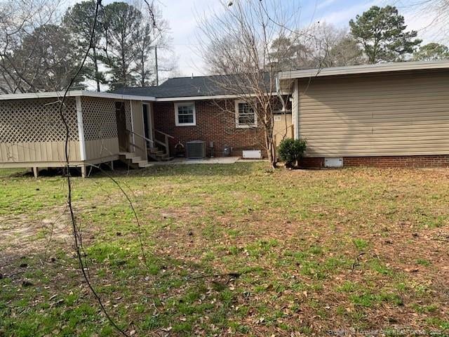 rear view of house featuring central AC unit, entry steps, and a yard