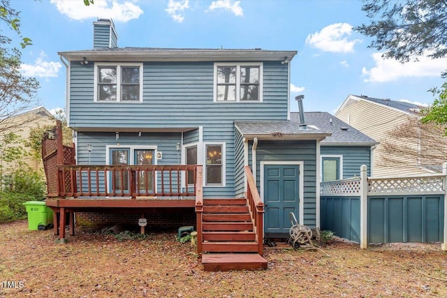 back of house with a deck, a chimney, and fence