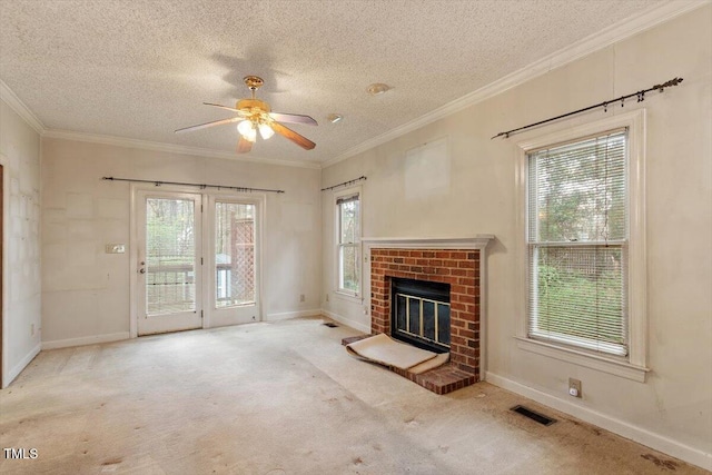 unfurnished living room with a textured ceiling, carpet flooring, ceiling fan, a brick fireplace, and crown molding