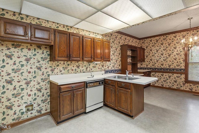 kitchen with white dishwasher, wallpapered walls, a sink, baseboards, and a peninsula