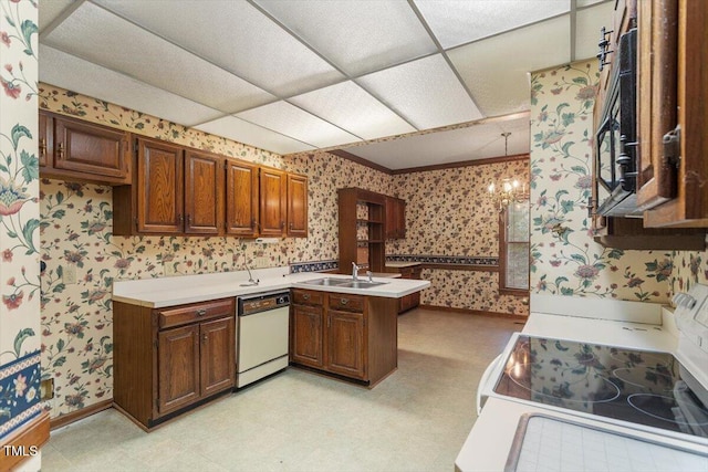 kitchen with wallpapered walls, white appliances, a peninsula, a sink, and light floors