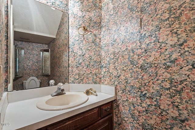 bathroom with wallpapered walls and vanity