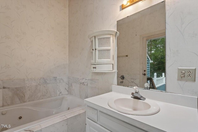 full bath featuring wallpapered walls, a jetted tub, and vanity