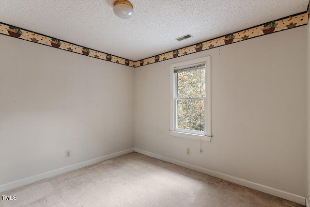 spare room with light carpet, baseboards, and a textured ceiling