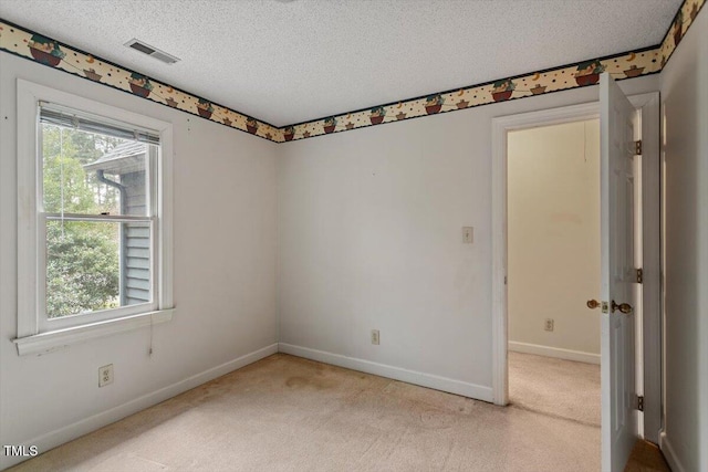 unfurnished room with carpet, healthy amount of natural light, a textured ceiling, and baseboards