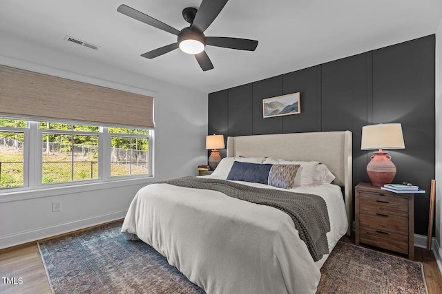 bedroom featuring visible vents, baseboards, wood finished floors, and a ceiling fan