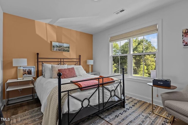 bedroom featuring visible vents, baseboards, and wood finished floors