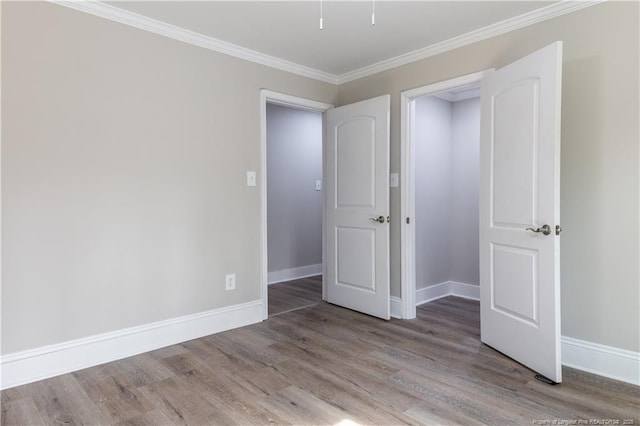 unfurnished bedroom with wood finished floors, baseboards, and crown molding