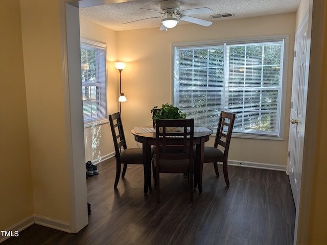 dining area with dark wood finished floors, visible vents, a textured ceiling, and a ceiling fan