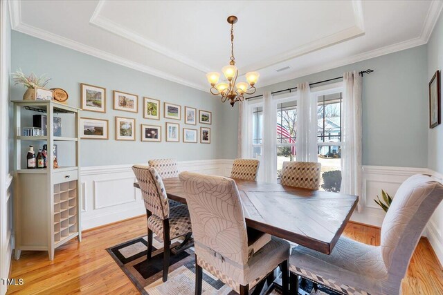 1624 Struble Cir, Willow Springs, NC 27592 - dining room with a raised ceiling, a chandelier, light wood-style floors, a wainscoted wall, and ornamental molding