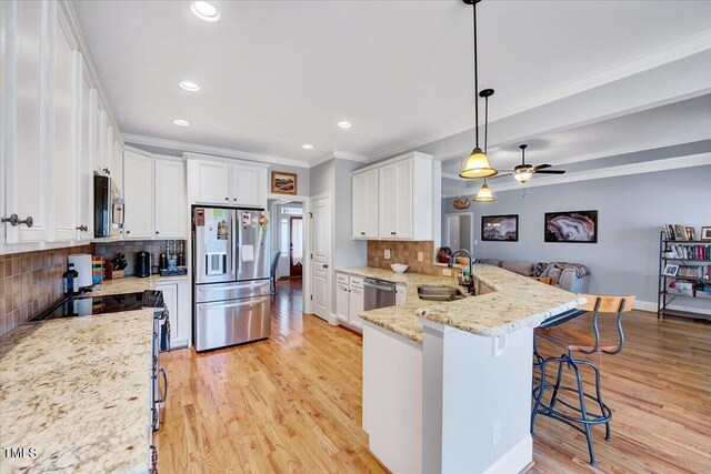 1624 Struble Cir, Willow Springs, NC 27592 - kitchen featuring appliances with stainless steel finishes, a peninsula, white cabinetry, ornamental molding, and a breakfast bar