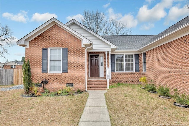 view of front facade featuring crawl space, brick siding, a front lawn, and fence