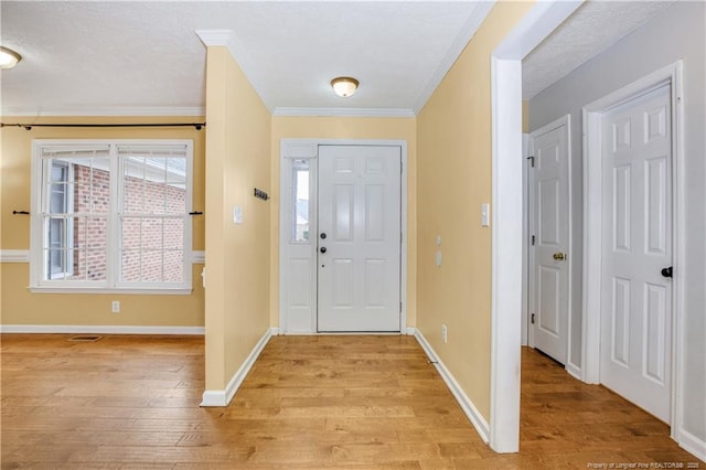 entryway with baseboards, crown molding, and light wood-style floors