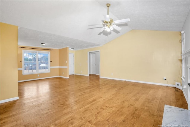 unfurnished living room with a ceiling fan, baseboards, light wood finished floors, vaulted ceiling, and a textured ceiling