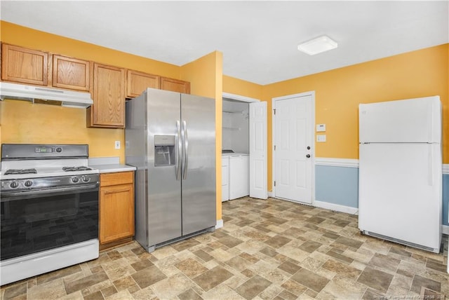 kitchen featuring white appliances, separate washer and dryer, light countertops, stone finish floor, and under cabinet range hood