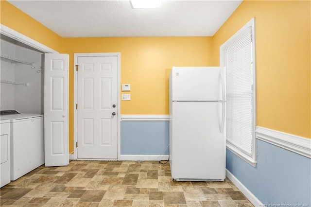 laundry area featuring stone finish floor, laundry area, independent washer and dryer, and baseboards