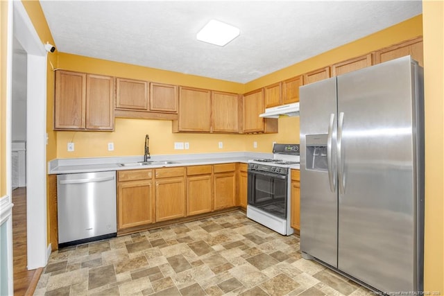 kitchen with a sink, stainless steel appliances, light countertops, under cabinet range hood, and a textured ceiling