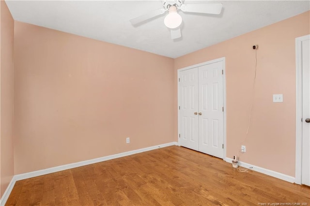 unfurnished bedroom featuring a ceiling fan, wood finished floors, baseboards, and a closet