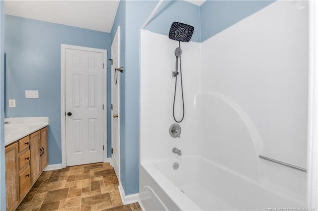 full bathroom featuring vanity, shower / bath combination, baseboards, and stone finish flooring