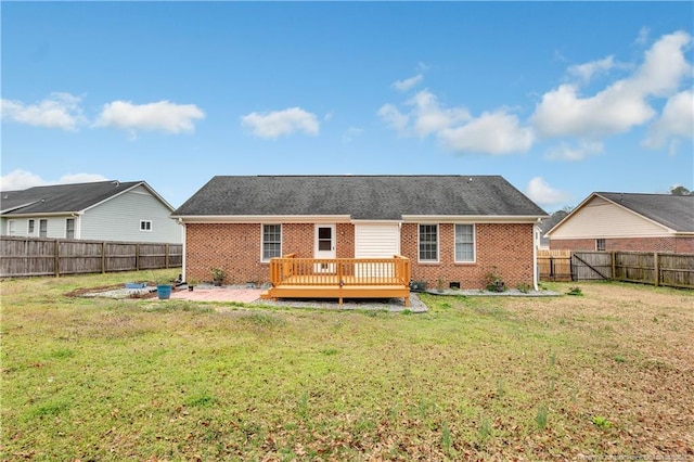 rear view of house with a wooden deck, brick siding, a fenced backyard, and a lawn