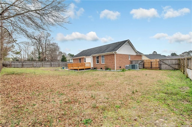 rear view of house with a yard, a fenced backyard, crawl space, a deck, and brick siding