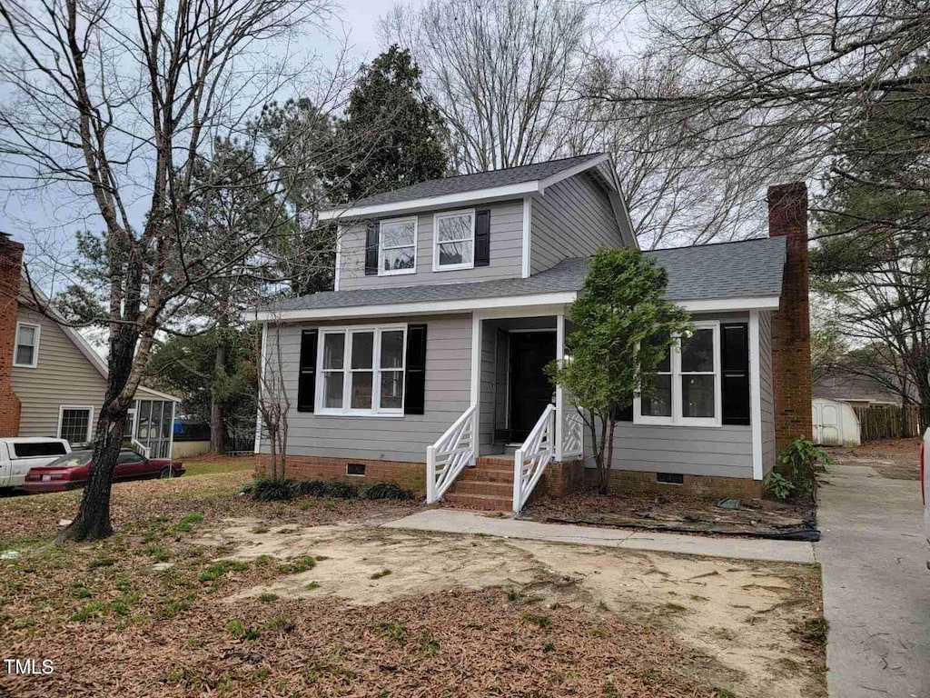 view of front of house with crawl space, a storage shed, roof with shingles, and an outdoor structure