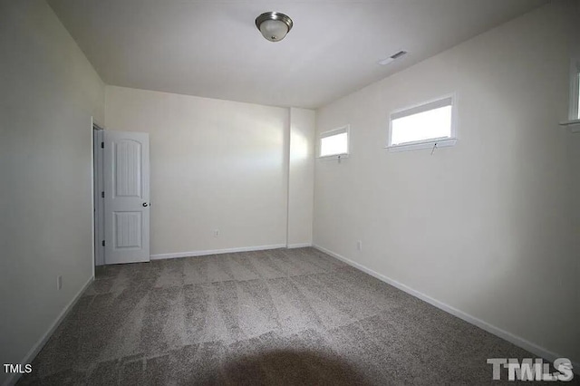 spare room with carpet flooring, visible vents, and baseboards