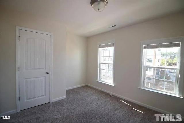 unfurnished room with visible vents, baseboards, and carpet floors