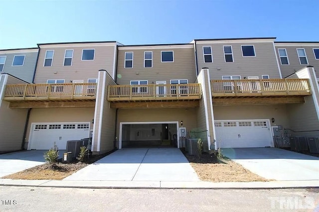 back of house with concrete driveway, an attached garage, and central AC unit