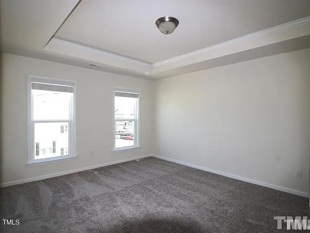 unfurnished room featuring dark carpet, baseboards, a tray ceiling, and ornamental molding