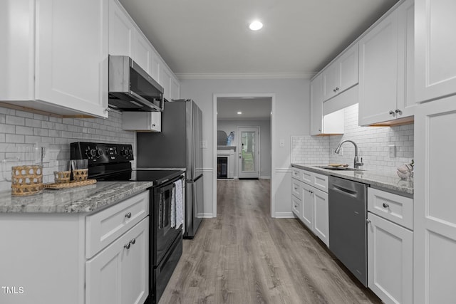 kitchen featuring light wood finished floors, appliances with stainless steel finishes, white cabinetry, and a sink