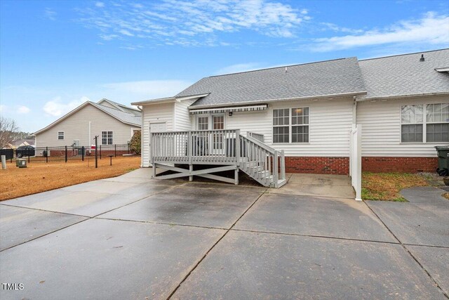 back of property featuring a wooden deck, roof with shingles, and fence