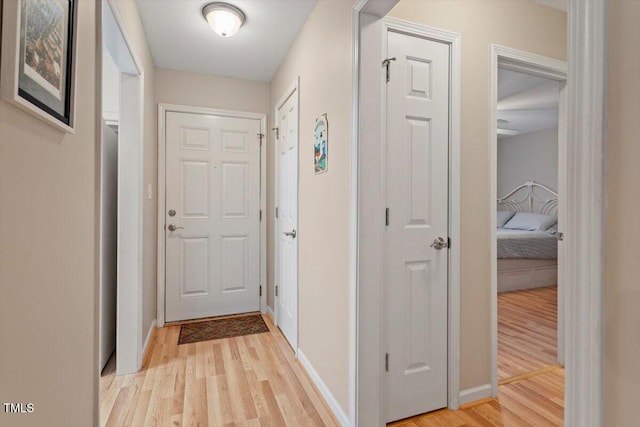 hallway featuring baseboards and light wood-style floors