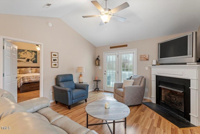 living room featuring light wood-style floors, a fireplace, lofted ceiling, and a ceiling fan
