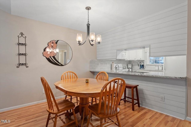 dining area featuring baseboards, light wood-style floors, and an inviting chandelier