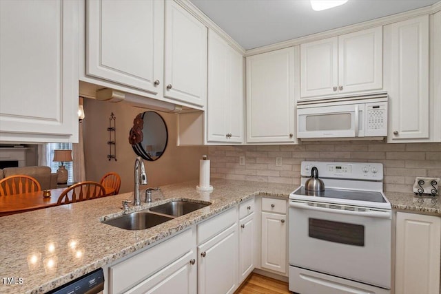 kitchen featuring decorative backsplash, white appliances, white cabinetry, and a sink