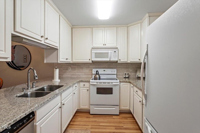 kitchen with light wood-style flooring, a sink, white appliances, decorative backsplash, and light stone countertops
