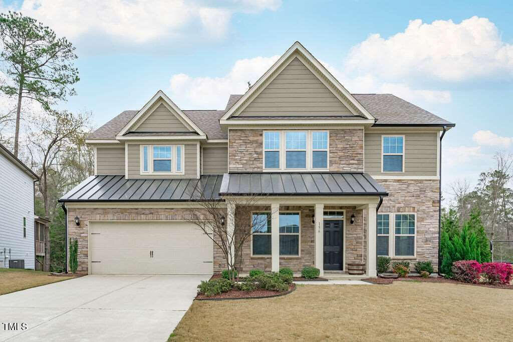 craftsman-style home featuring stone siding, an attached garage, concrete driveway, and a standing seam roof