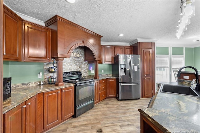 kitchen featuring black appliances, brown cabinets, light wood finished floors, and a sink