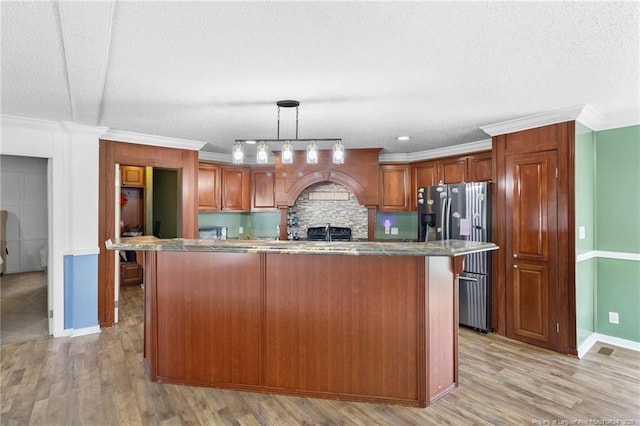 kitchen featuring stainless steel refrigerator with ice dispenser, a textured ceiling, light wood-style floors, crown molding, and hanging light fixtures