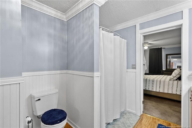 ensuite bathroom with connected bathroom, a textured ceiling, wainscoting, and crown molding