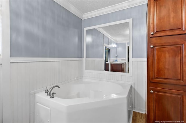 full bathroom featuring wainscoting, a textured ceiling, a garden tub, and ornamental molding