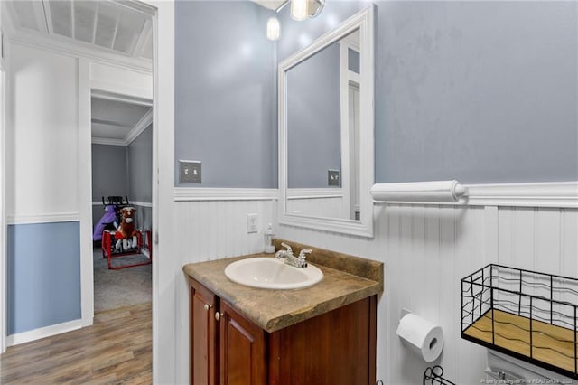 bathroom with vanity, wood finished floors, and wainscoting