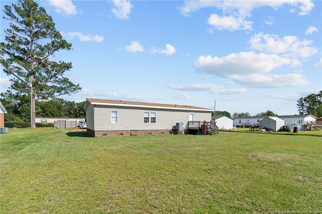 rear view of house with crawl space and a lawn