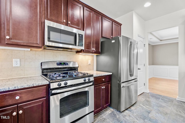 69 Florence Dr, Clayton, NC 27527 - kitchen with a decorative wall, appliances with stainless steel finishes, light stone counters, reddish brown cabinets, and wainscoting