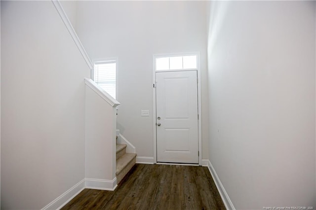 doorway to outside with baseboards, dark wood-style floors, and stairway