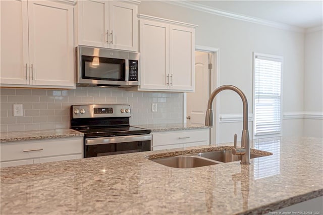 kitchen featuring a sink, appliances with stainless steel finishes, white cabinets, decorative backsplash, and ornamental molding