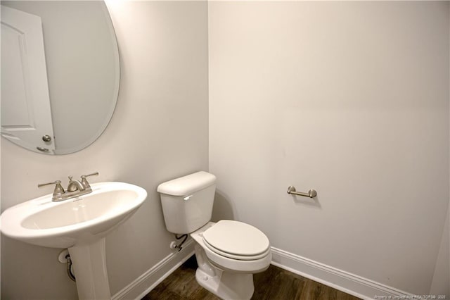 bathroom with baseboards, toilet, and wood finished floors